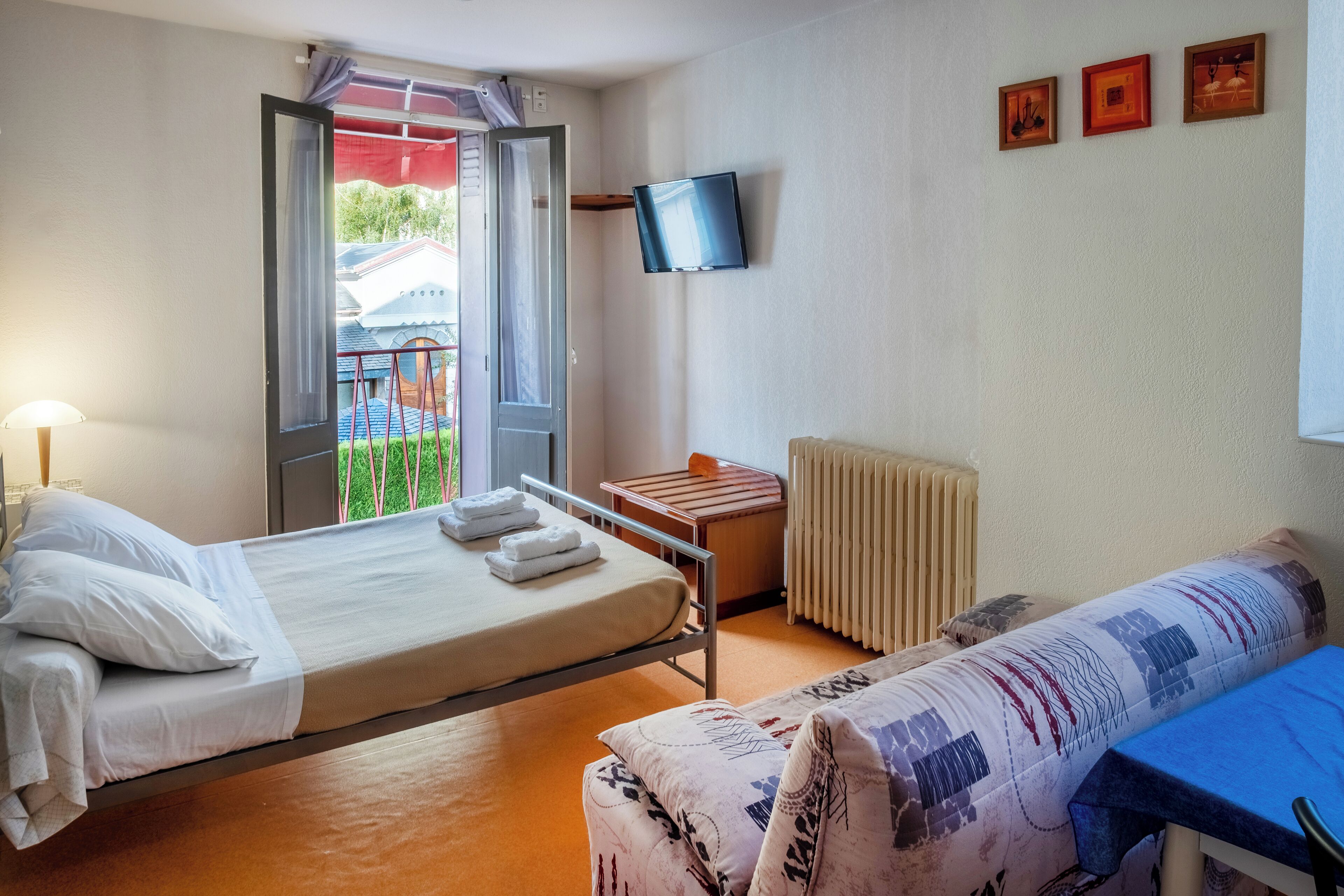 Habitación de hotel con cama, una mesita, una silla, televisor y ventana con vistas al exterior.