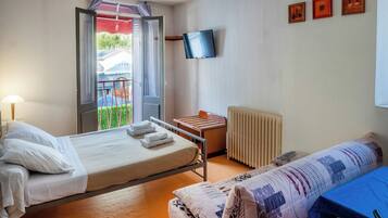 Habitación de hotel con cama, una mesita, una silla, televisor y ventana con vistas al exterior.