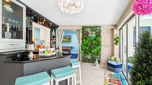 A modern kitchen with a bar area, a green vertical garden, and a colorful rug. - Waterfront w/ Htd Pool, Tiki Hut, Billards, & Bar (Boynton Beach)