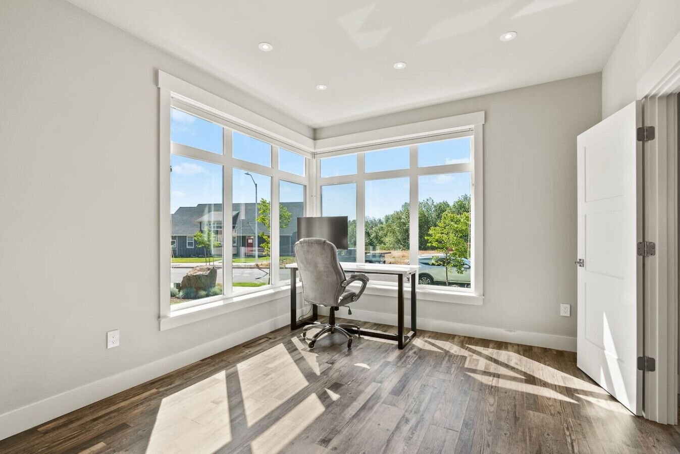 A room with large windows, a desk, and a chair.