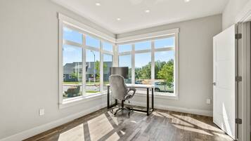 A room with large windows, a desk, and a chair.