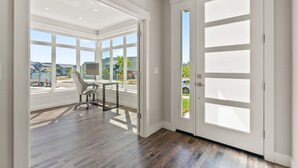 Una habitación amplia con ventanas grandes, un escritorio y una silla.