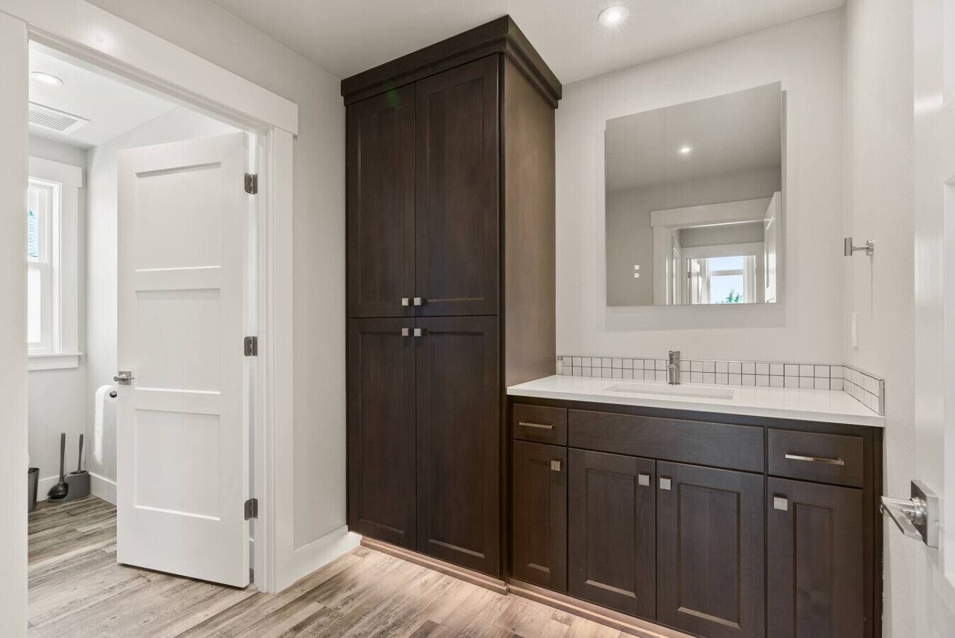 A bathroom with dark wooden cabinets, a white sink, and a large mirror.