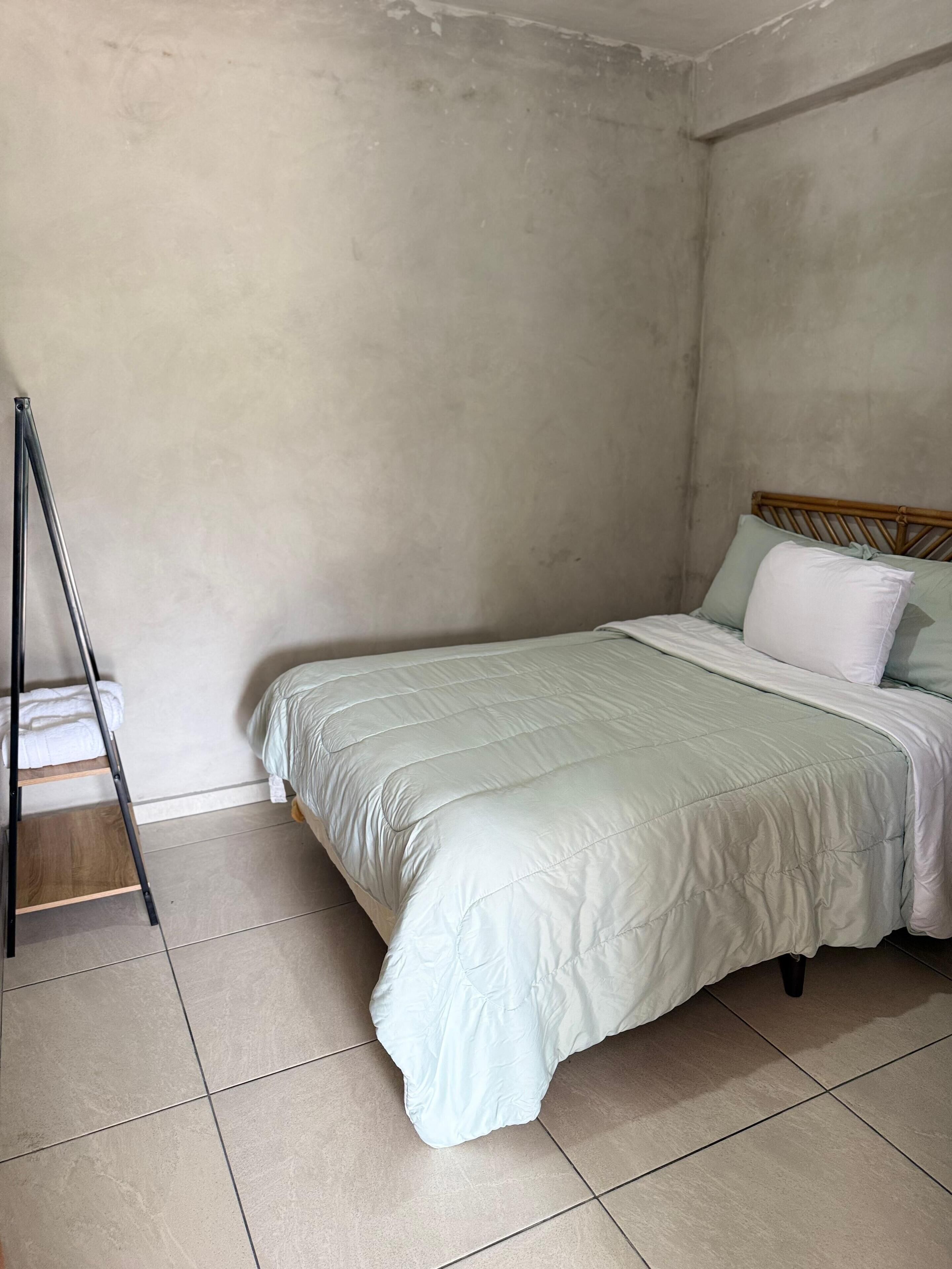 Une chambre à coucher avec un lit, une échelle en bois et un mur uni.