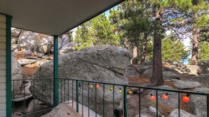 Un espace extérieur abrité, agrémenté de gros rochers, de pins et d’une rambarde en métal.