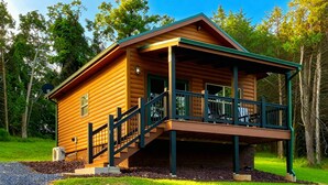 Une cabane en bois dotée d’un porche et d’un escalier menant à une terrasse.