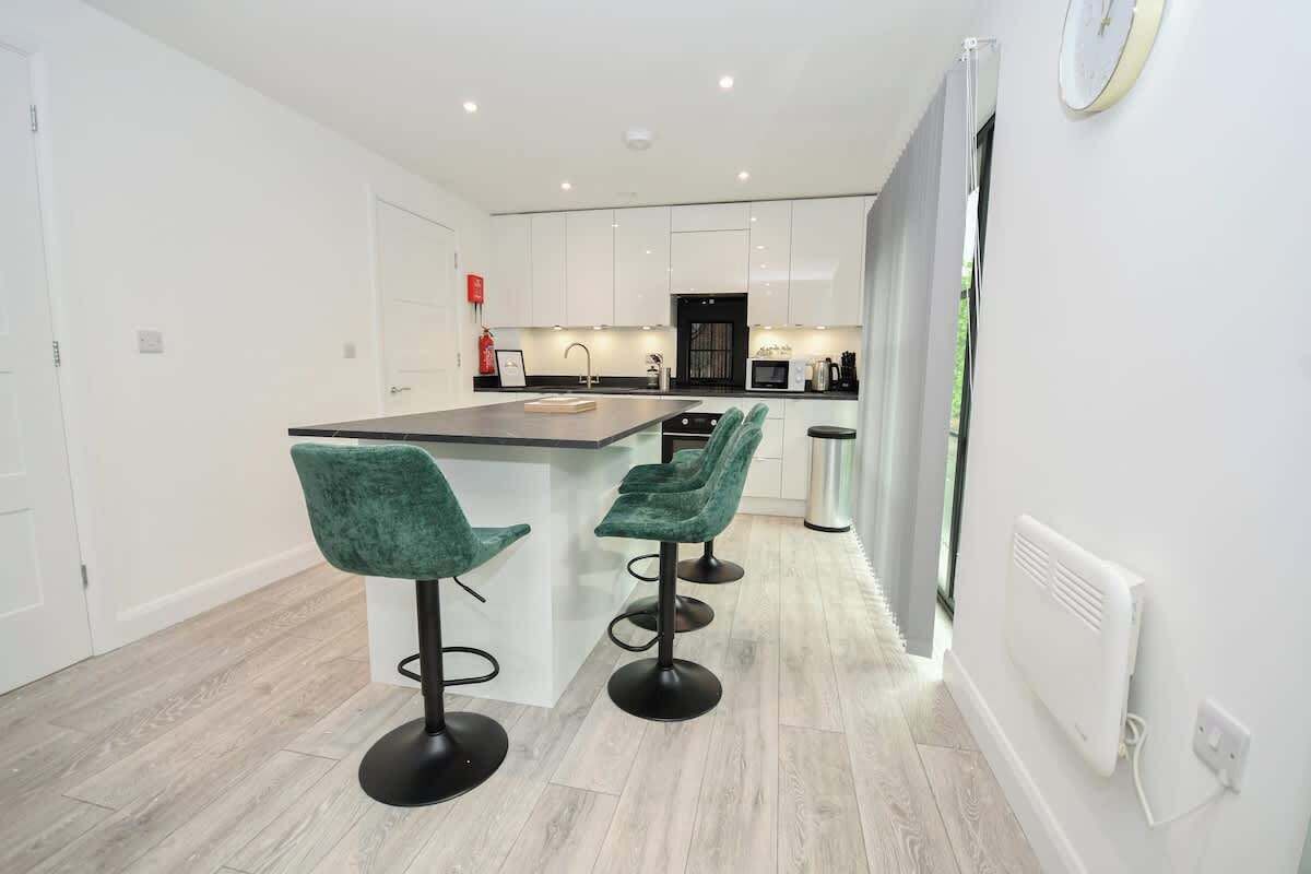 A modern kitchen with white cabinets, a central island, and bar stools.