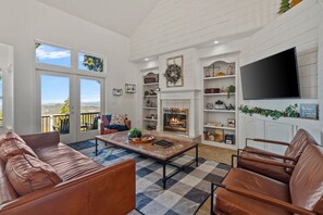 A living room with a fireplace, a television, and a view of the outdoors.