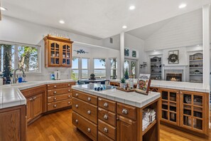 A spacious kitchen with wooden cabinets, a central island, and a fireplace.