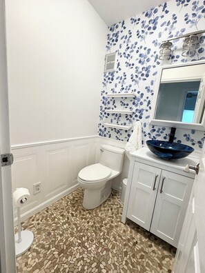 Une salle de bain avec des toilettes, un lavabo doté d’un receveur bleu et un miroir au-dessus du lavabo.