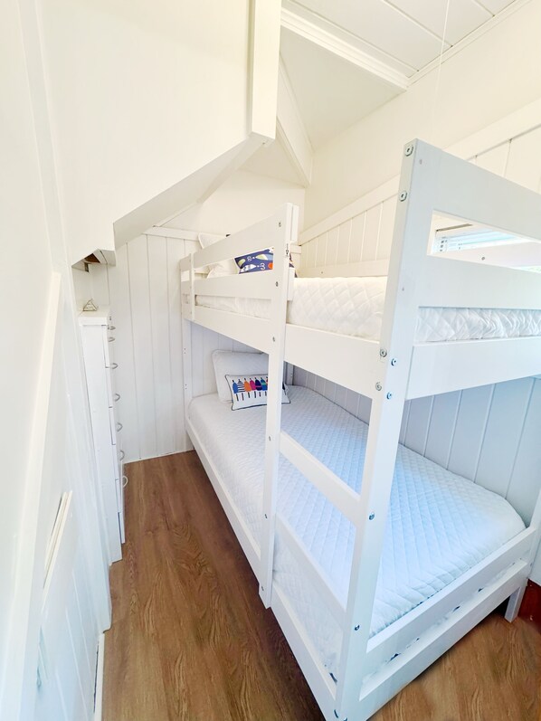 A bunk bed room with white walls and wooden flooring. - Charming 3-bedroom cottage steps to the ocean in beautiful Wells with AC (Wells)