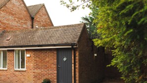 A brick house with a dark door, a small porch, and a potted plant. - Aethelred Annexe - New Build with Full Amenities (Winchester)