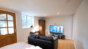 A hotel room with a large bed, a television, a desk, and a window. - Aethelred Annexe - New Build with Full Amenities (Winchester)