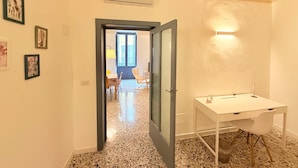 A hallway with a white desk, a chair, and a door leading to a balcony. - Typical old house in the heart of Triggiano (Triggiano)
