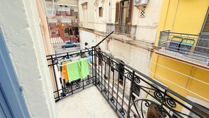 A balcony with a metal railing, a hanging laundry rack, and a yellow building in the background. - Typical old house in the heart of Triggiano (Triggiano)