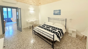 A bedroom with a bed, a desk, a chair, and a painting on the wall. - Typical old house in the heart of Triggiano (Triggiano)