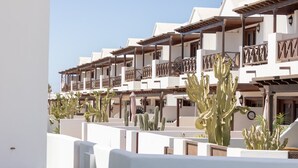 Een hotel met meerdere balkons, witte muren en cactussen.