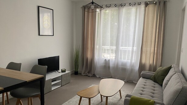 Moderni olohuone, jossa on sohva, sohvapöytä, televisio sekä ruokailutila tuoleineen ja pöytineen.