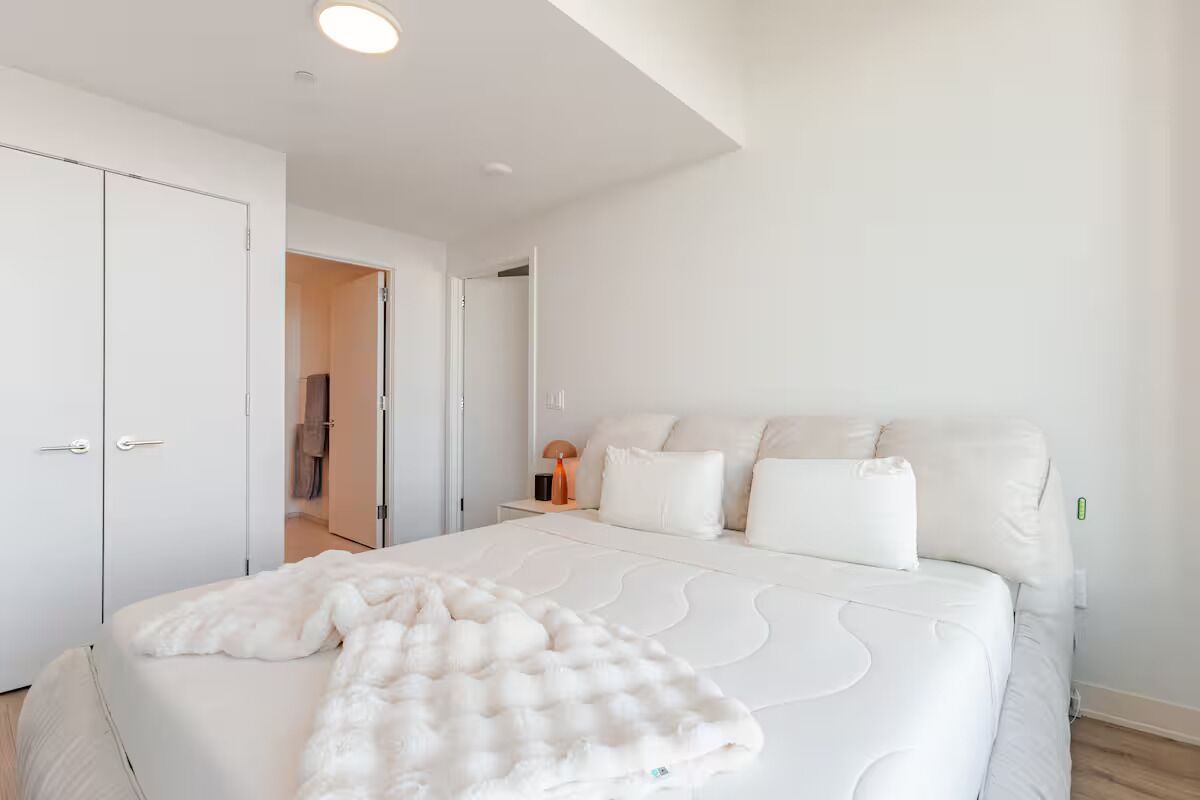 A modern bedroom with a large bed, white walls, and a minimalist design.