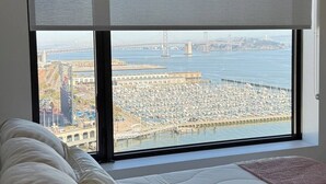 A bedroom with a large window overlooking a marina and a bridge.