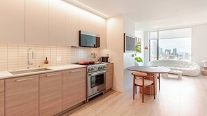 A modern kitchen with a built-in oven, a microwave, and a large window overlooking a cityscape.