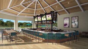 Un amplio espacio al aire libre con bar, múltiples opciones de asientos, una barra central y un techo alto con vigas de madera.