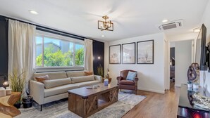 Un salon moderne avec un canapé, un fauteuil, une table basse et des œuvres d’art accrochées aux murs.