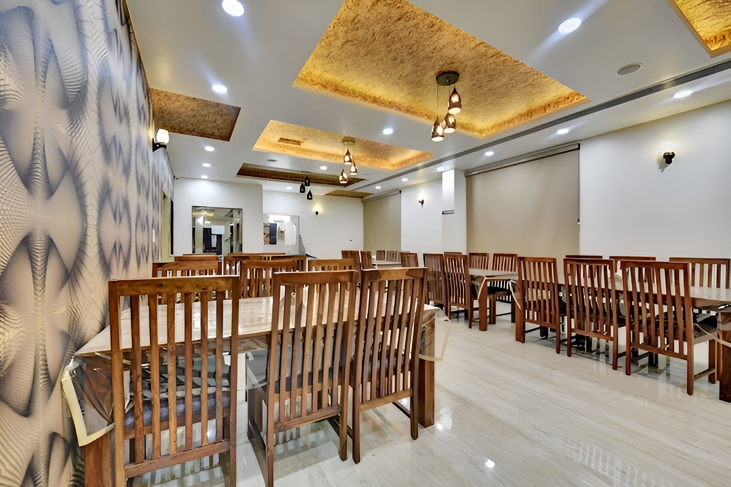 A spacious dining area with wooden tables and chairs, recessed ceiling lights, and a modern design.