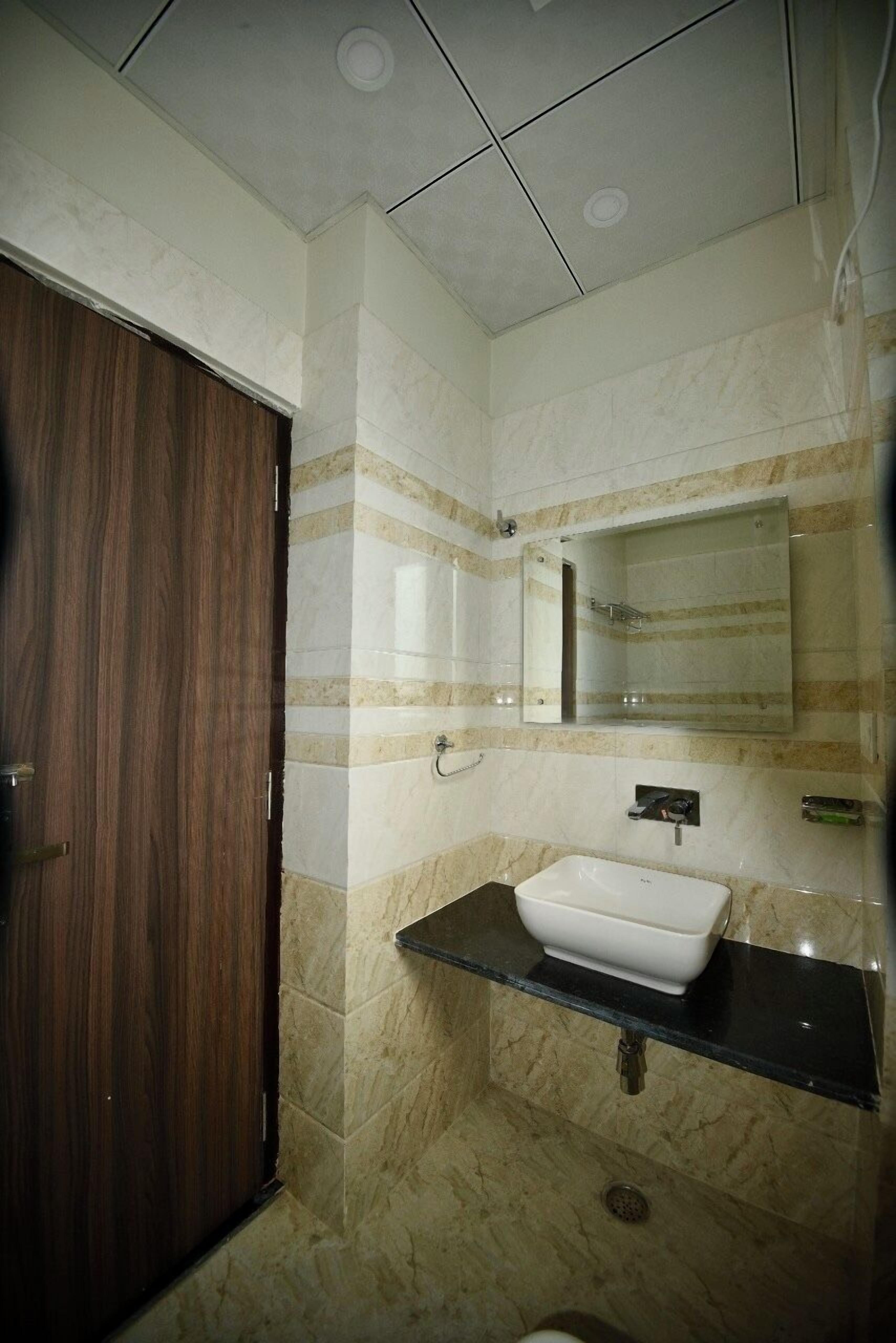 A bathroom with a wooden door, a white sink, and a mirror above it.