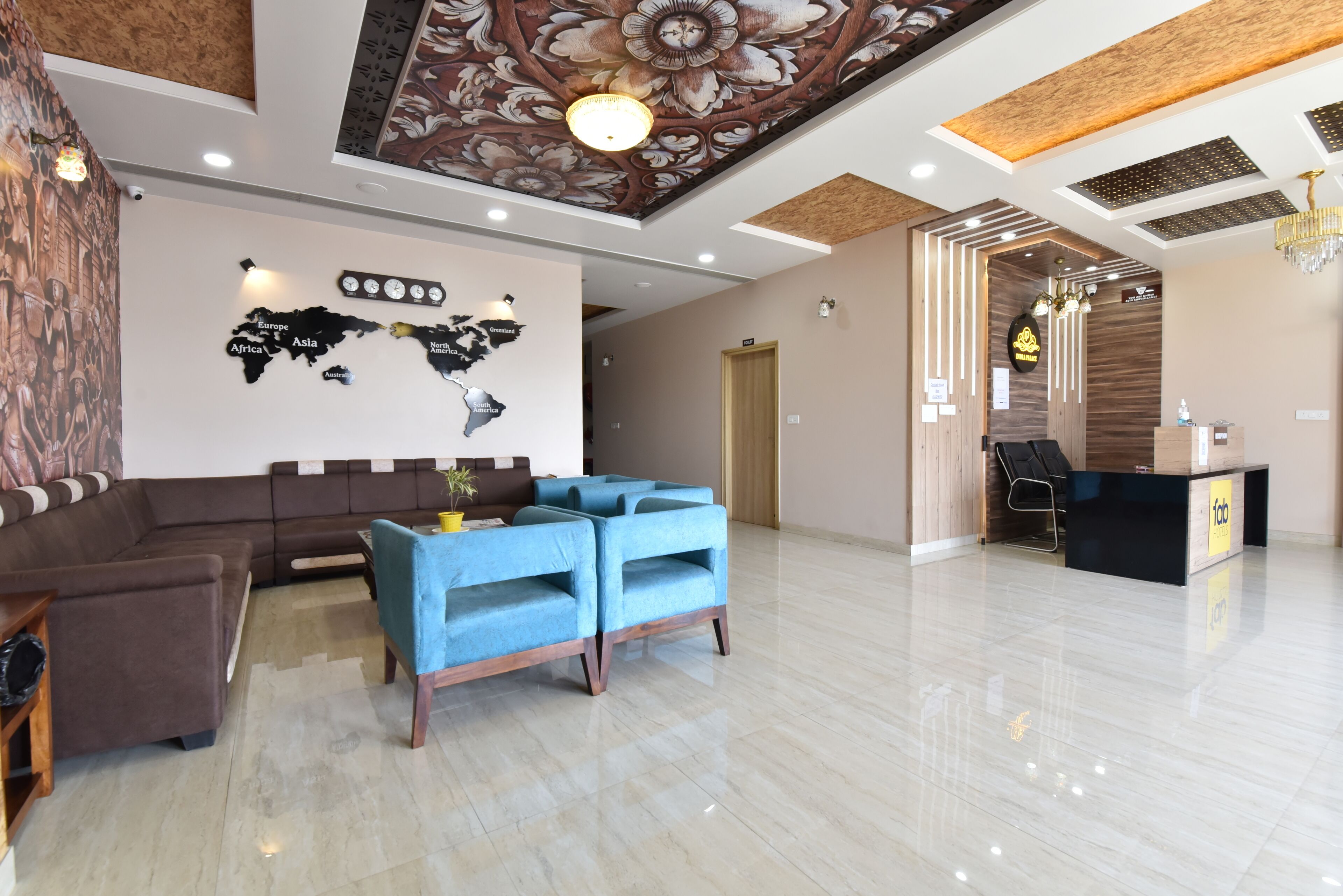 Un hall de hotel con mostrador de recepción, zona de estar y un mural de un mapa mundial.