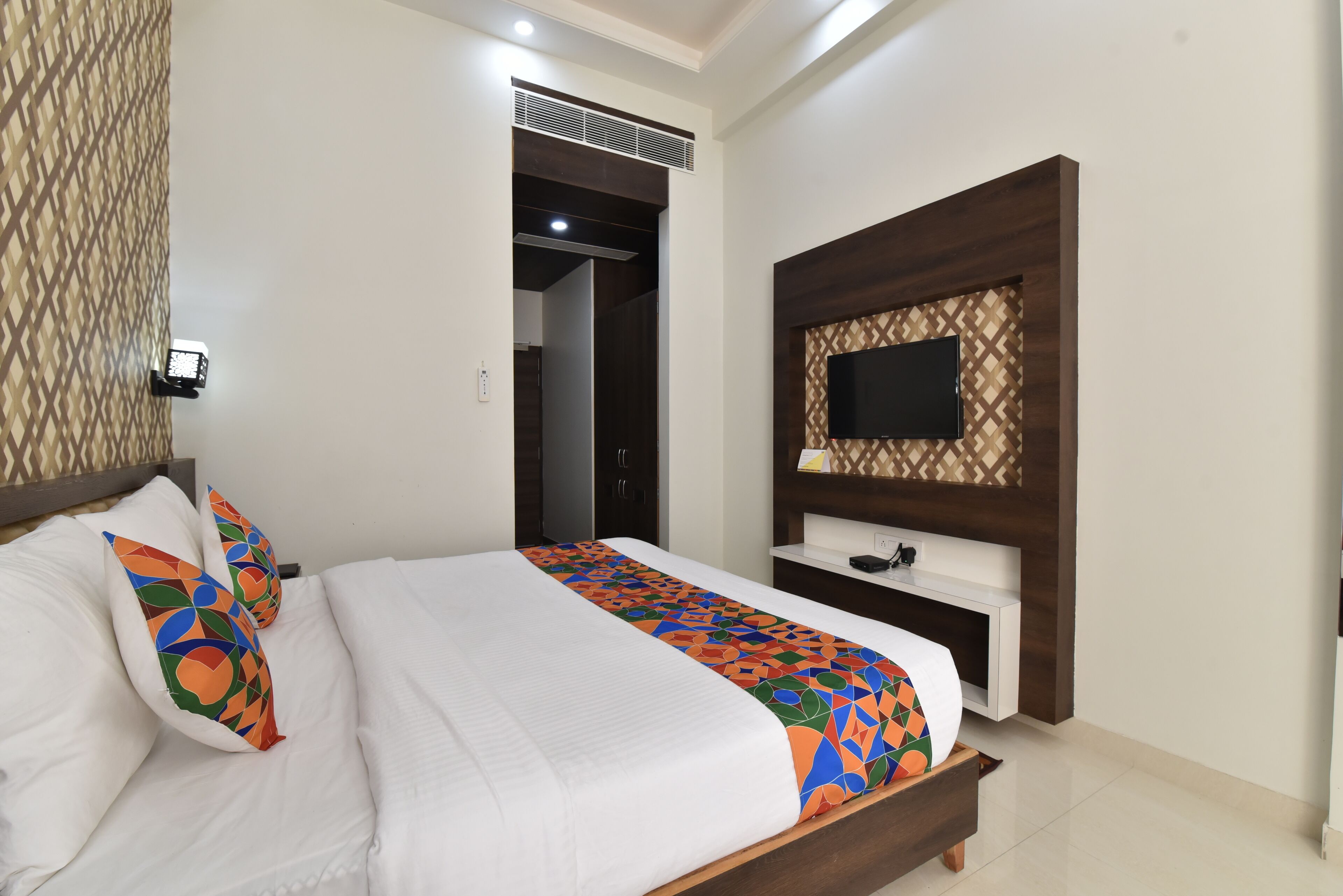 Una habitación de hotel con una cama, un televisor montado en la pared y un diseño de pared estampado.