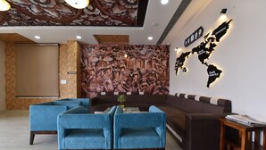 A lobby with a sofa, two blue armchairs, a world map on the wall, and a 'No Smoking' sign. - INDRA PALACE (Jaipur)