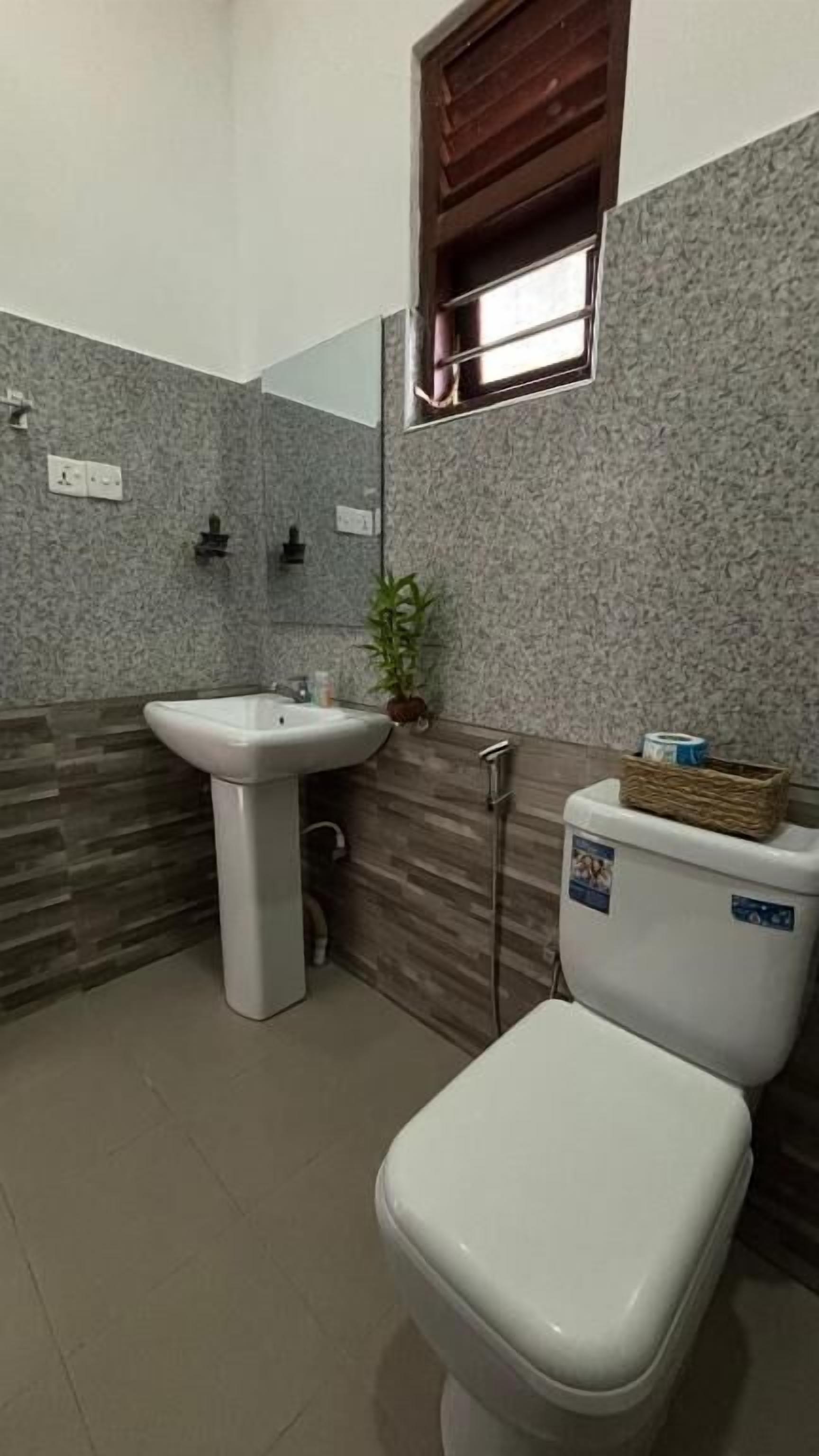 A bathroom with a white sink, a toilet, and a small window.