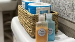 Une salle de bain dotée d’un comptoir en granit, d’un lavabo et d’un panier en osier contenant des articles de toilette.