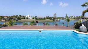 Une piscine avec vue sur un lac et des maisons en arrière-plan.