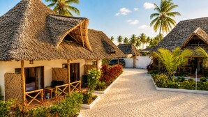 Um resort com cabanas de telhado de palha, um calçadão e palmeiras.