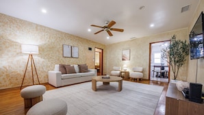 A spacious living room with a white sofa, a coffee table, and a ceiling fan.