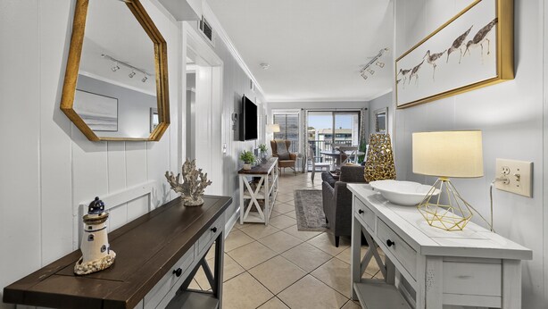 A modern kitchen with a white countertop, a wooden bench, and a large mirror. - Coco Cabana - 4th Floor w/ Indoor & Outdoor Pools! (Hilton Head)