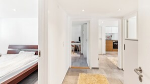 Ein modernes Hotelzimmer mit einem Holzbett, einer Küchenzeile und einem durch eine offene Tür einsehbarer Badezimmer.