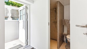 Ein Badezimmer mit Dusche, Toilette und einem Fenster zum Balkon.