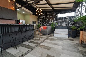 Una cocina moderna con barra, un sofá gris y una pared estampada.