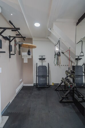 Un gimnasio con equipo de levantamiento de pesas, un saco de boxeo y un espejo.