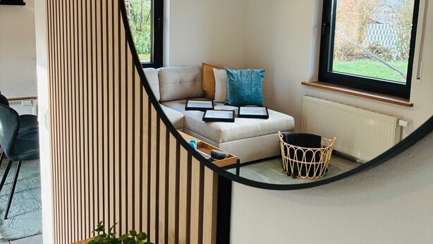 Ein modernes Interieur mit einer Couch, einer Hängelampe und Blick durch ein Fenster.