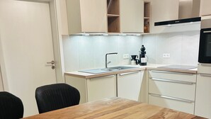 Eine Küche mit einem Holztisch, weißen Schränken und einer schwarzen Kaffeemaschine.