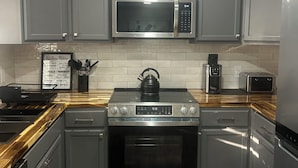 A modern kitchen with grey cabinets, a stainless steel microwave, a gas stove, and a built-in oven. - Newly Remodeled Home with Full Deck and Gazebo. (Jackson)
