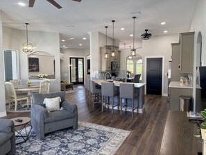 A modern kitchen with a central island, bar seating, and pendant lighting. - Spacious 4-bedroom house with pool,  close to beaches, shopping and restaurants (North Port)