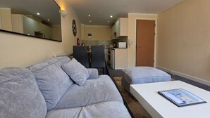 Un salon moderne avec un canapé gris, une table basse blanche et un coin repas à l’arrière-plan.