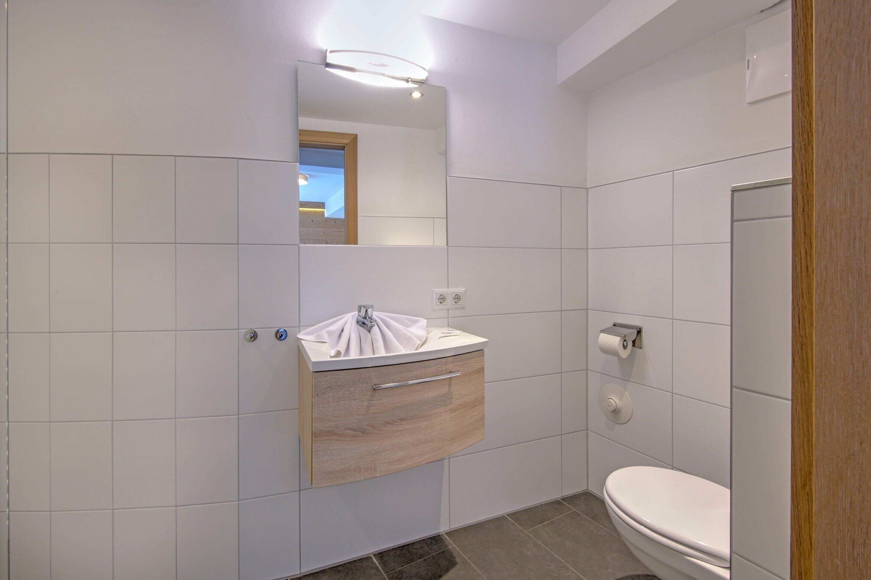 Une salle de bain moderne avec un lavabo blanc, un miroir et des toilettes.