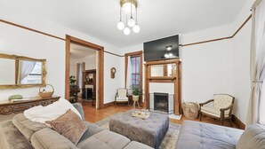 A living room with a fireplace, sofas, a television, and a chandelier. - Historic Tower Grove Retreat (St. Louis)