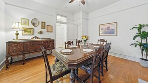 A dining room with a wooden table set for four, surrounded by chairs, a ceiling fan, and a potted plant. - Historic Tower Grove Retreat (St. Louis)